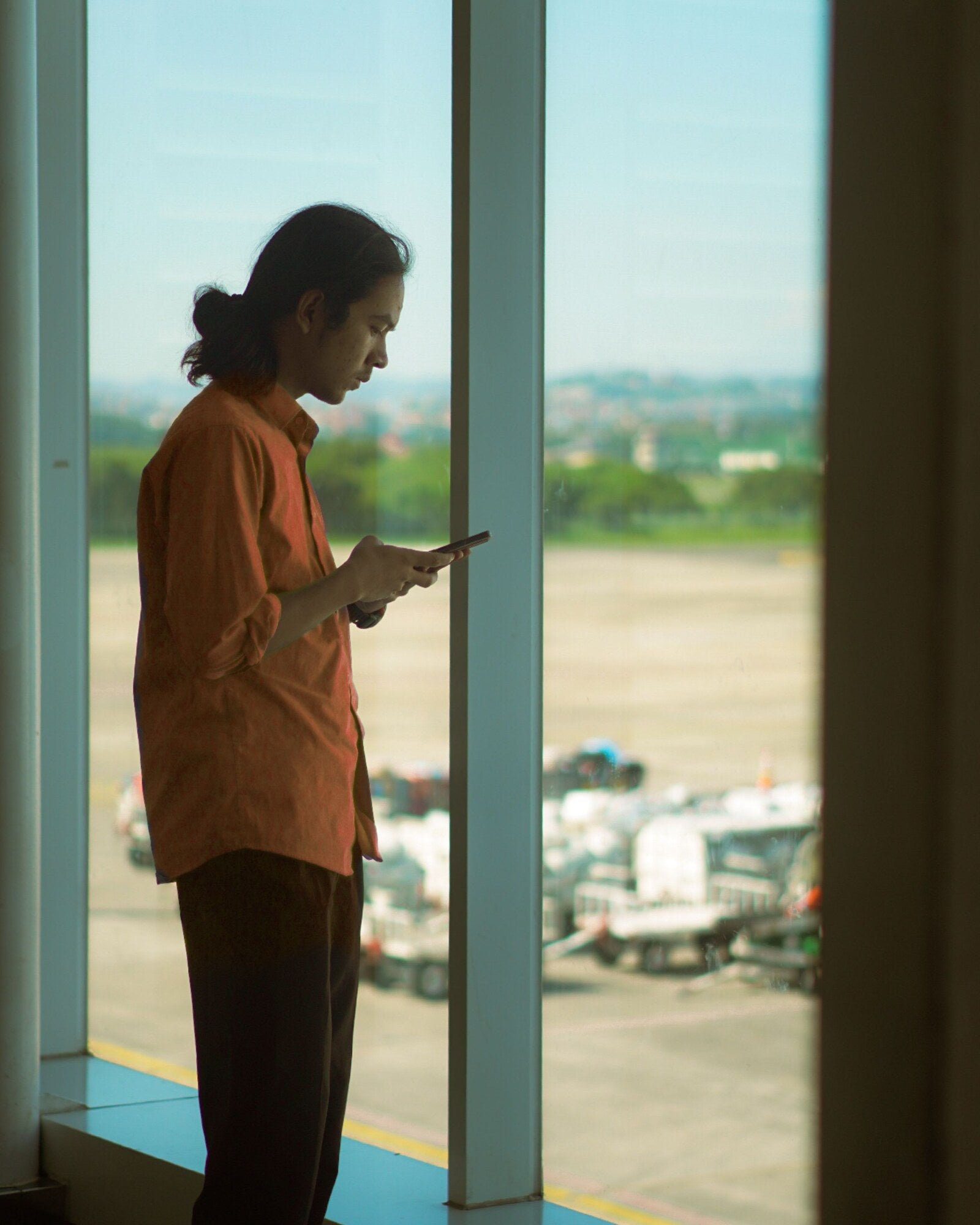 Traveller using a phone beside an airport window before a flight